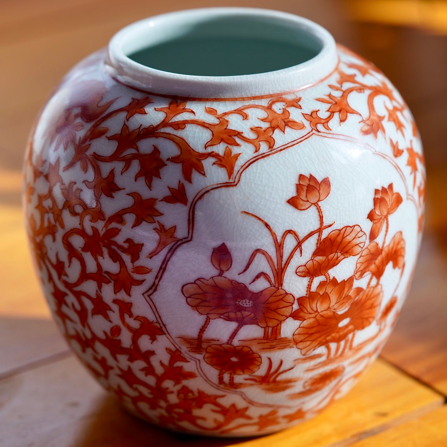 Vintage white and orange handpainted Japanese porcelain vase with flowers, displayed on light wood floor.